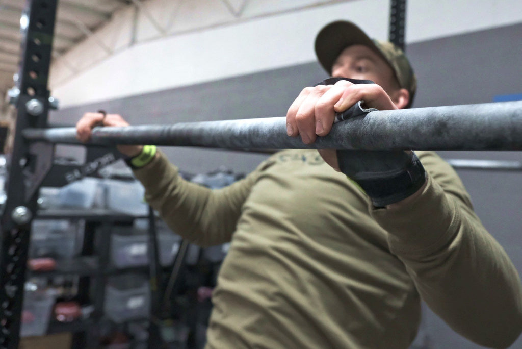 Man in olive shirt doing pull ups while wearing Bear Komplex Diamond 3-Hole Gymnastic Grips with Green Velcro Strap | FreeAthlete